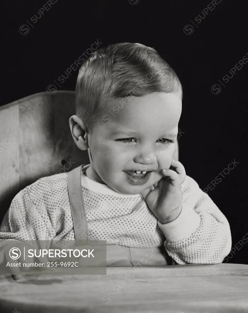 Close-up of a baby sitting in a high chair and smiling