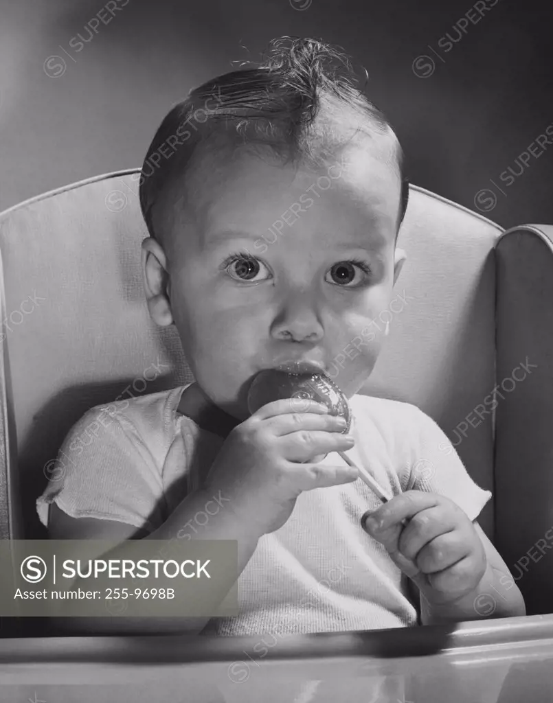 Portrait of a baby licking a lollipop