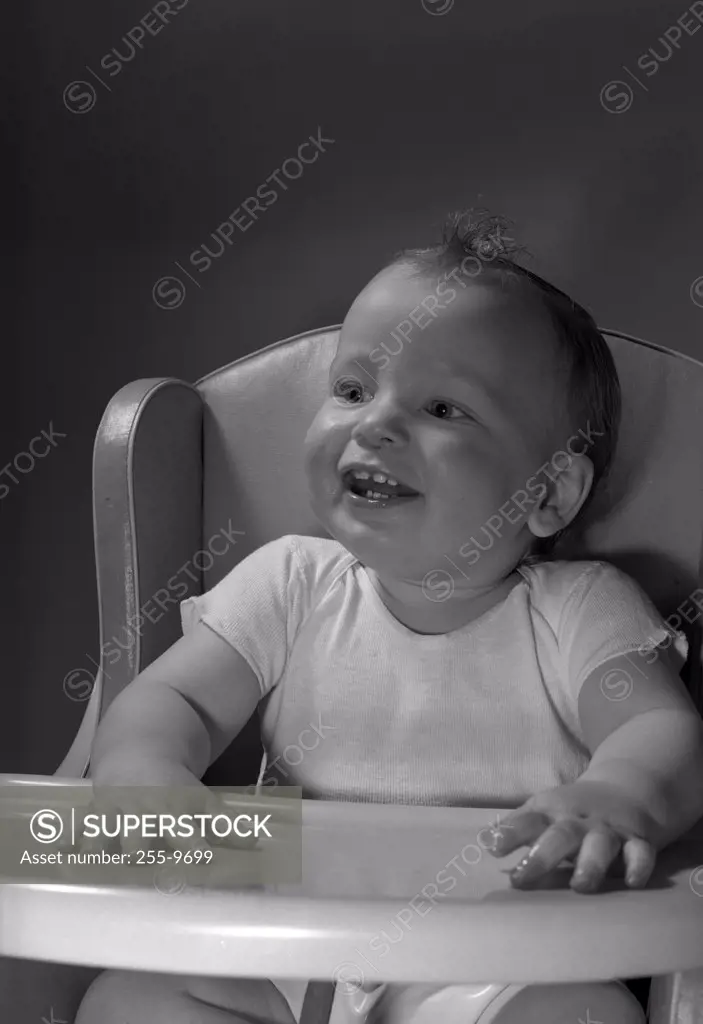 Baby sitting in high chair smiling