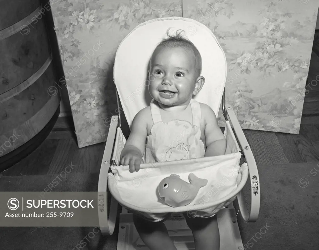 Vintage photograph. Close-up of a baby sitting in a high chair and smiling