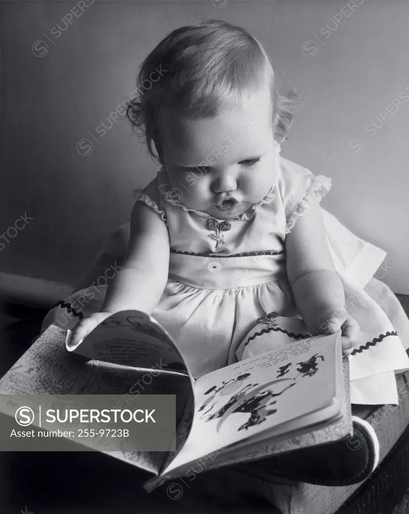 Close-up of a baby girl holding a picture book