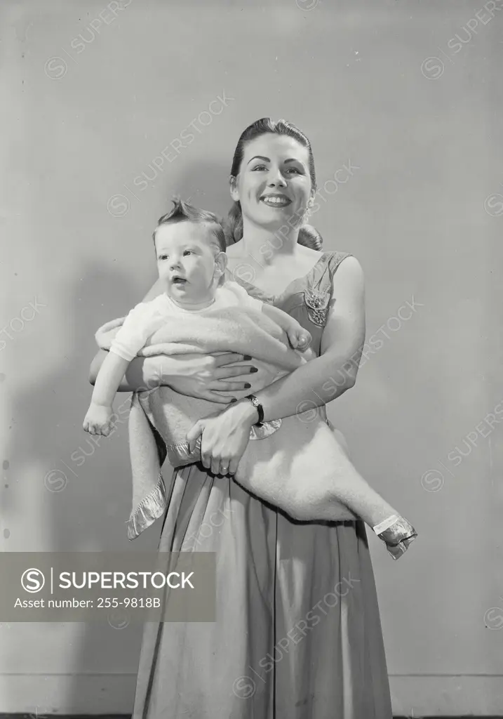 Vintage Photograph. Mother cradling her son swaddled in baby blanket and smiling