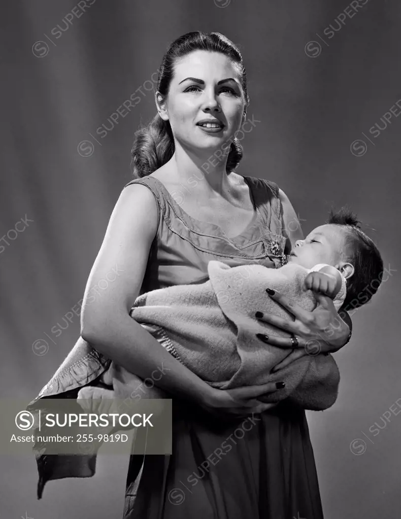 Portrait of mother carrying baby wrapped in blanket
