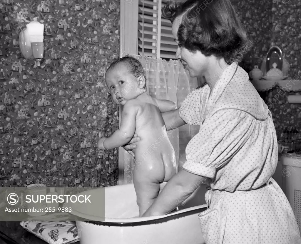 Young woman washing her baby in a washtub