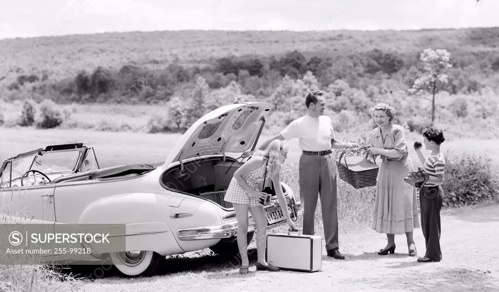 Parents and their children loading luggage into a car