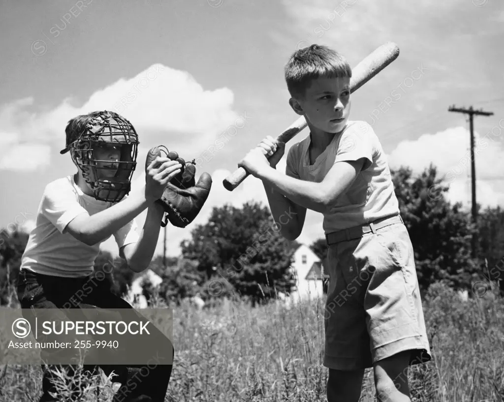 Two boys playing baseball in field