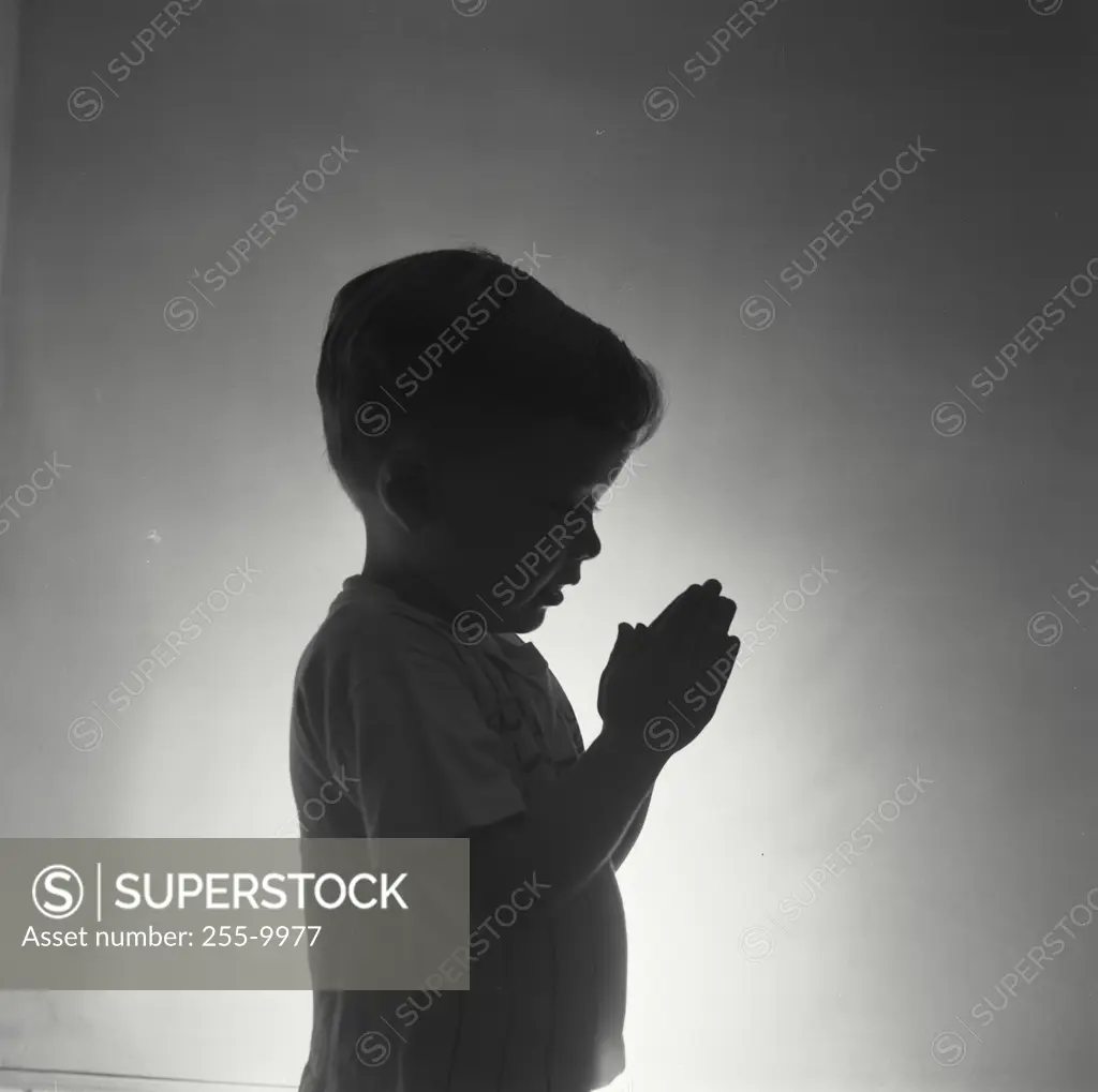 Vintage Photograph. Dramatic silhouette of little boy in pajamas saying his prayers. Frame 2