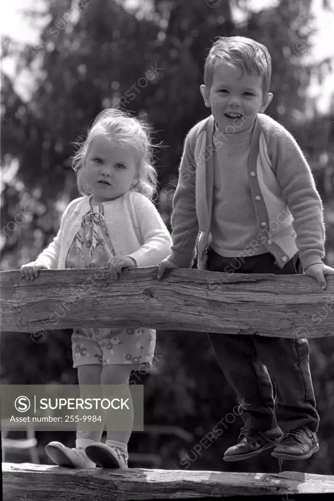 Boy and girl standing on rail fence