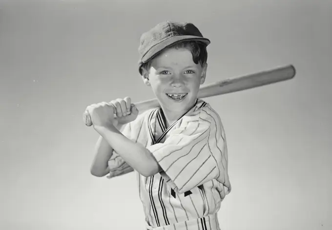 Vintage Photograph. Young boy wearing baseball uniform holding bat over shoulder