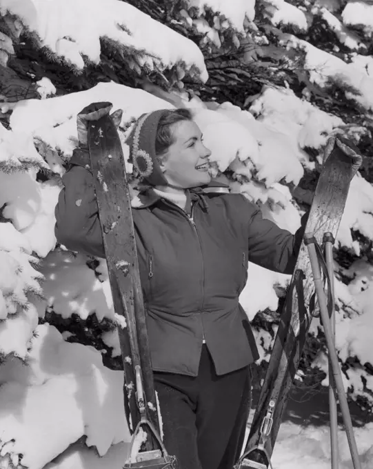 Young woman holding skis and smiling
