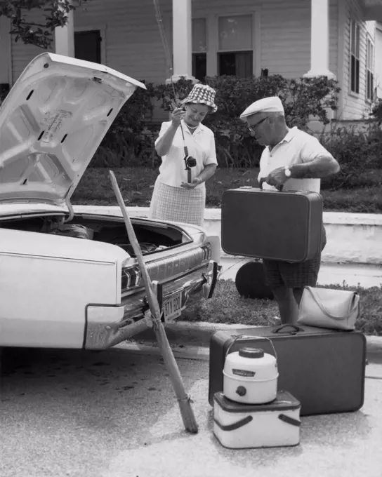 Senior couple loading luggage into a car trunk