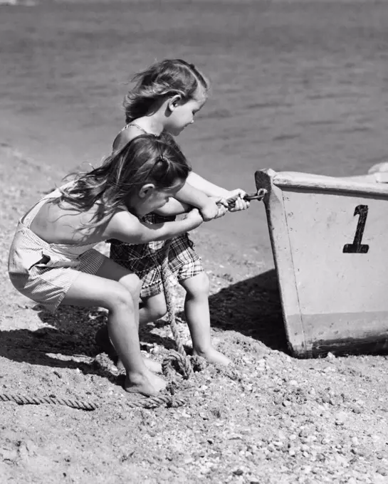 Two girls pulling a boat by a rope on the beach