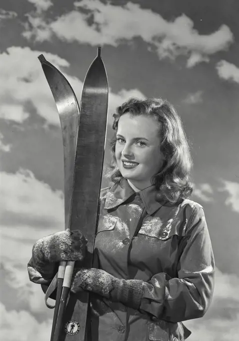 Vintage Photograph. Portrait of a young woman holding skis