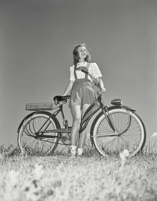 Vintage Photograph. Woman on bicycle in field looking off camera