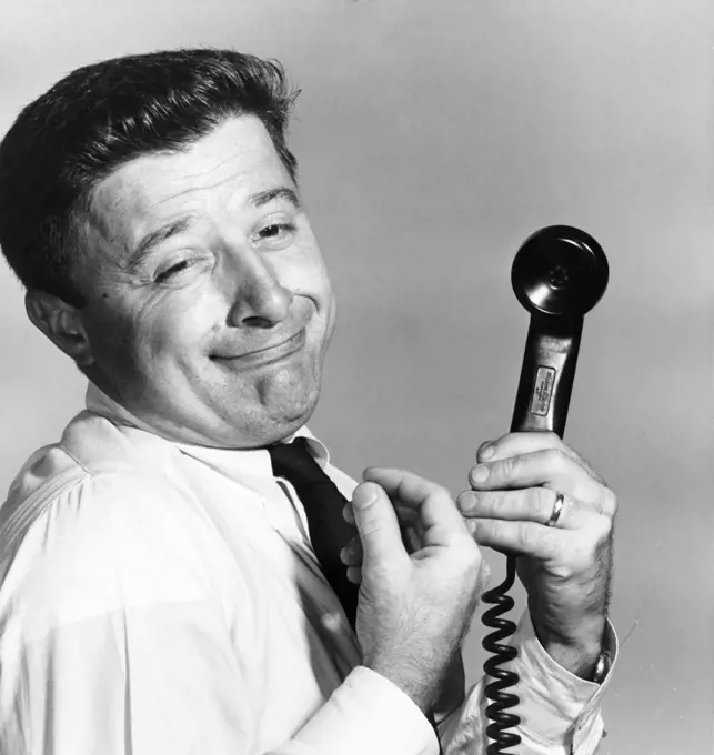 Side profile of a businessman holding a telephone receiver making a face