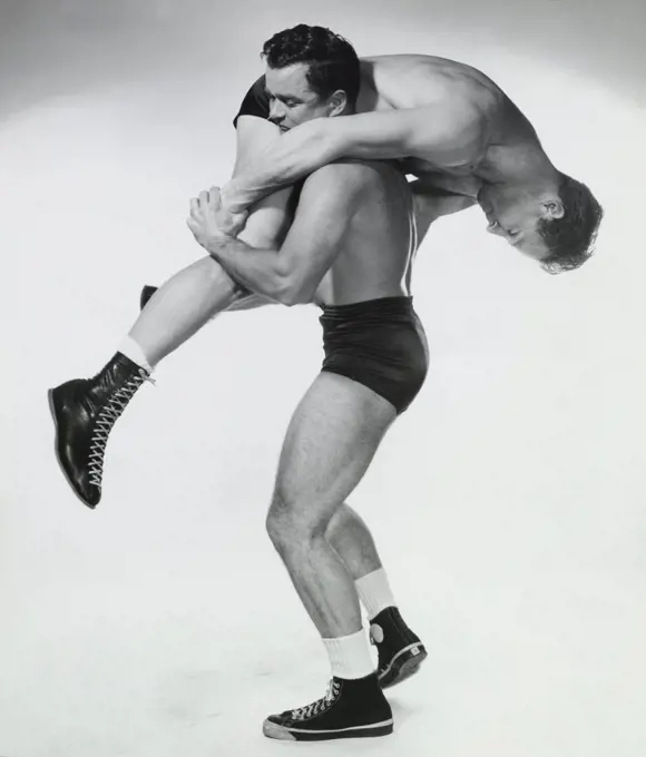 Two young adult men wrestling