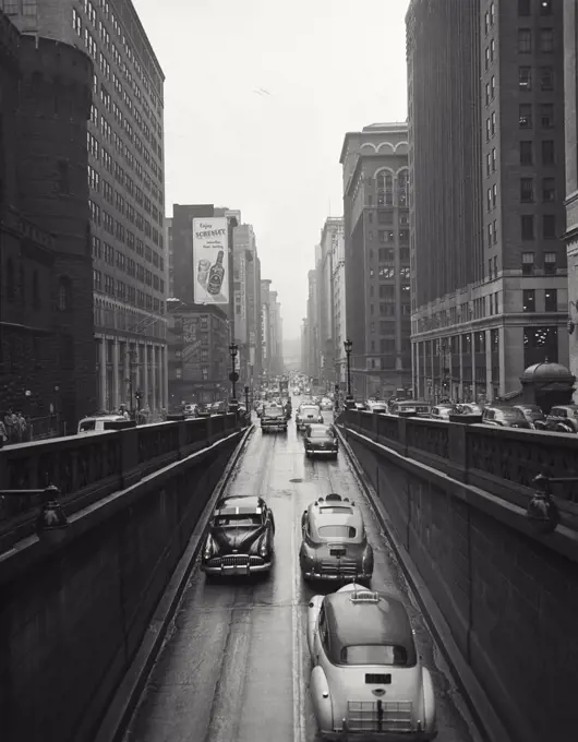 Vintage photograph. Rainy day, Park Avenue ramp below grand Central Station. Cars. Taxi.