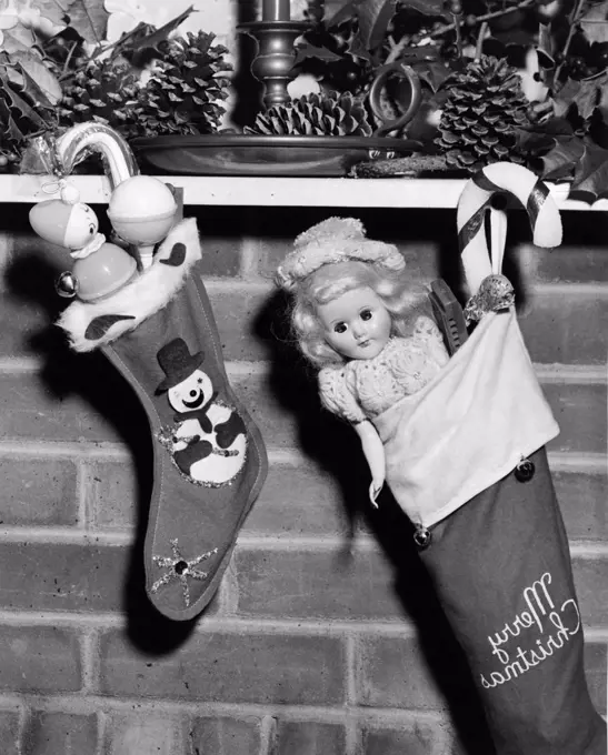 Close-up of two Christmas stockings filled with toys hanging from a mantelpiece