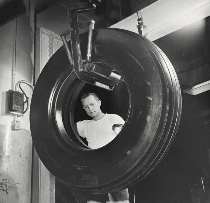 Vintage photograph. Inspecting an airplane bomber tire at a US Rubber Company plant