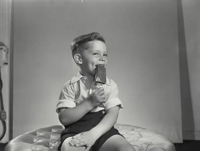 Vintage photograph. Little boy biting ice cream pop.