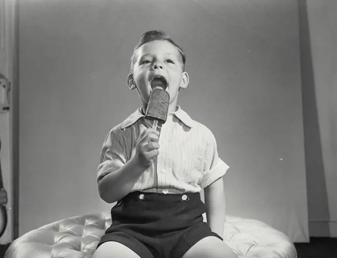 Vintage photograph. Little boy licking ice cream pop.