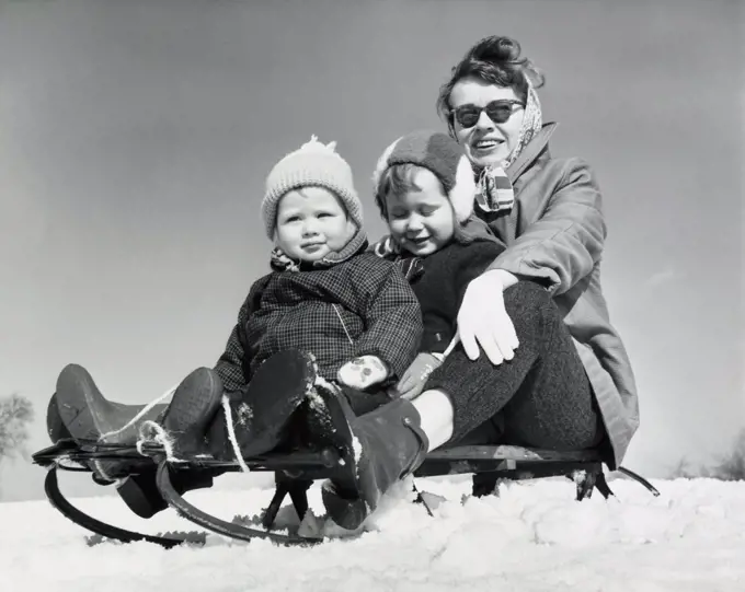 Close-up of a mother with her two children sitting on a sled