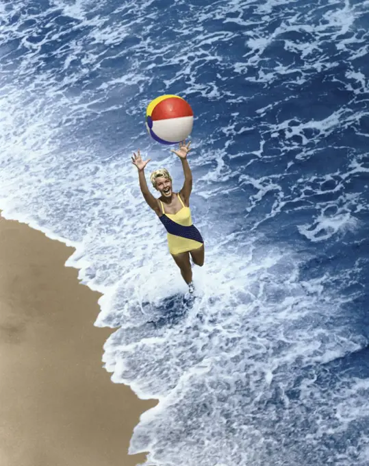 High angle view of a young woman playing with a beach ball on the beach