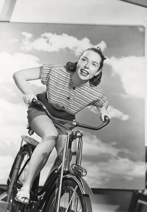 Vintage photograph. Low angle view of young woman riding bicycle