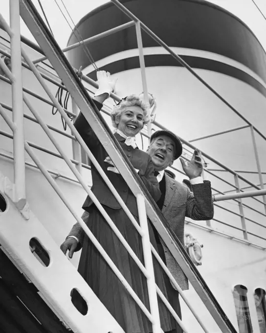Portrait of a senior couple waving from a ship