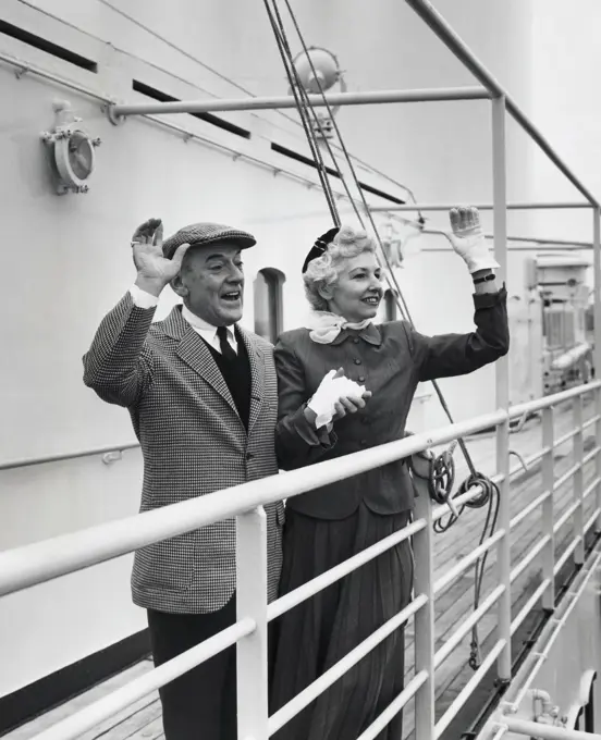 Senior couple standing on the deck of a cruise ship and waving