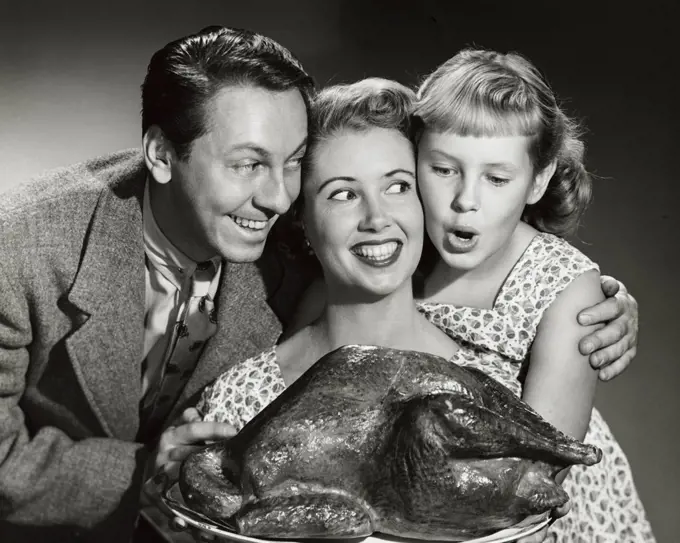 Portrait of a family holding a turkey on a platter