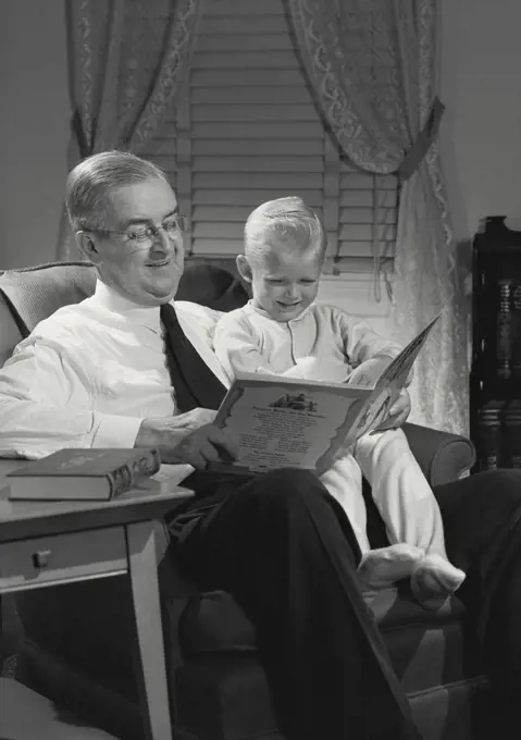 Vintage photograph. Man reading children's book to young boy