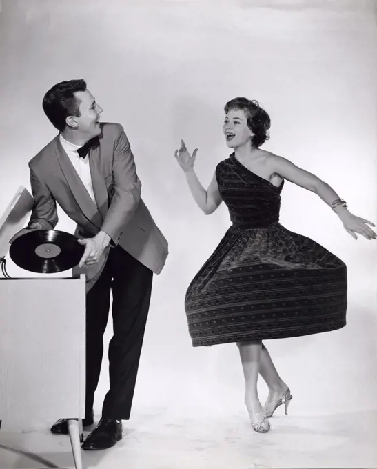 Young man holding a record looking at a young woman dancing near him