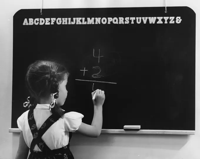 Rear view of a girl writing on a blackboard