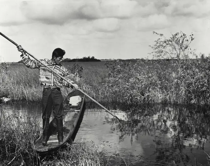 Vintage Photograph. USA, Florida, Everglades National Park, Seminole man spear fishing in lake