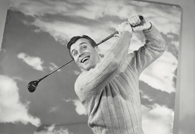 Vintage photograph. Close-up of a mid adult man swinging a golf club