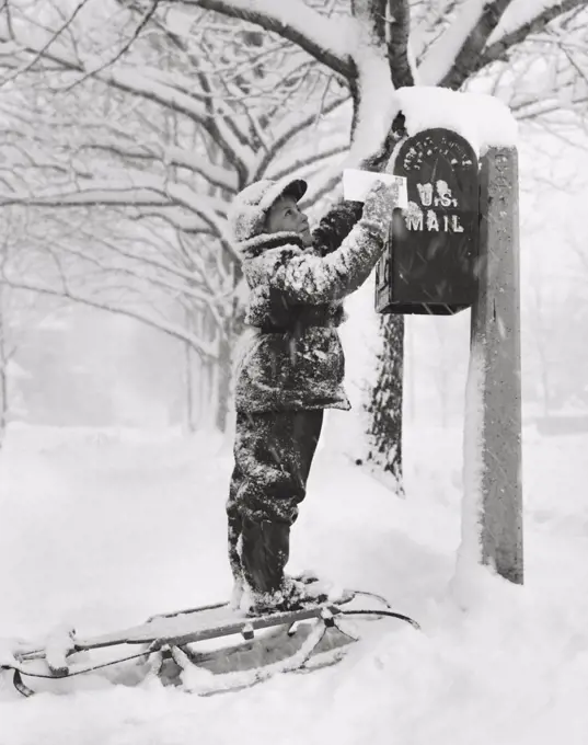 Boy putting a letter into a mailbox