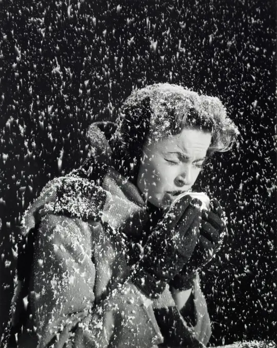 Side profile of a young woman sneezing in a snow fall
