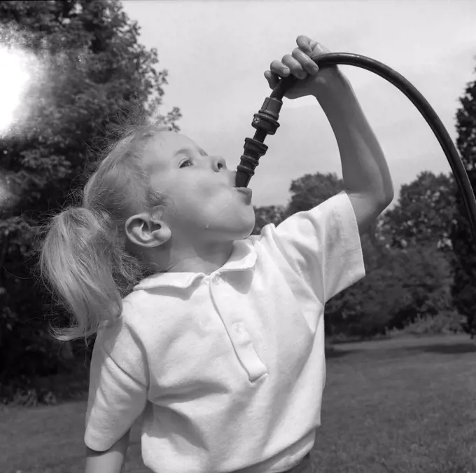 Girl drinking from garden hose