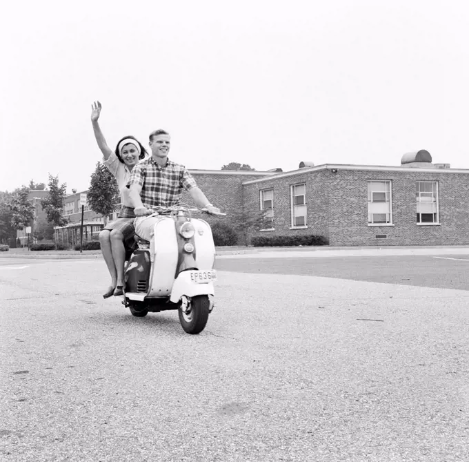 Young happy couple driving scooter