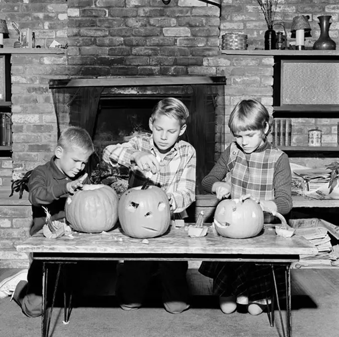 Girl and two boys preparing Jack O' Lantern for Halloween