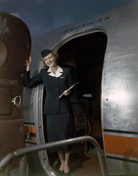 Airline hostess standing in doorway of plane