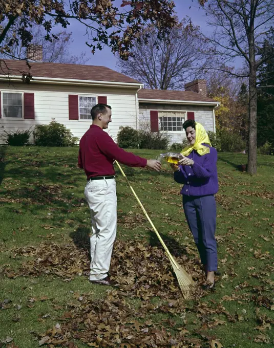 Couple raking leaves in backyard