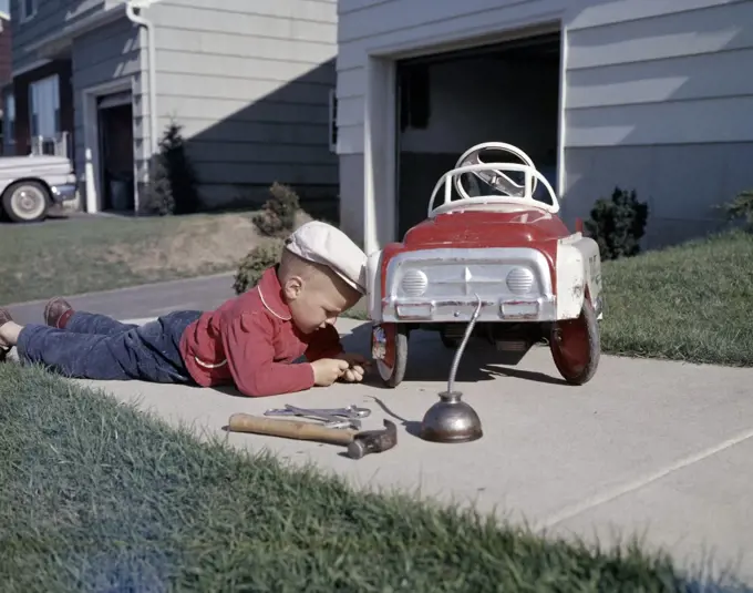 Boy repairing go-cart in yard