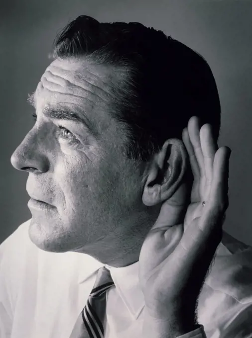 Close-up of a mature man with a cupped hand to his ear