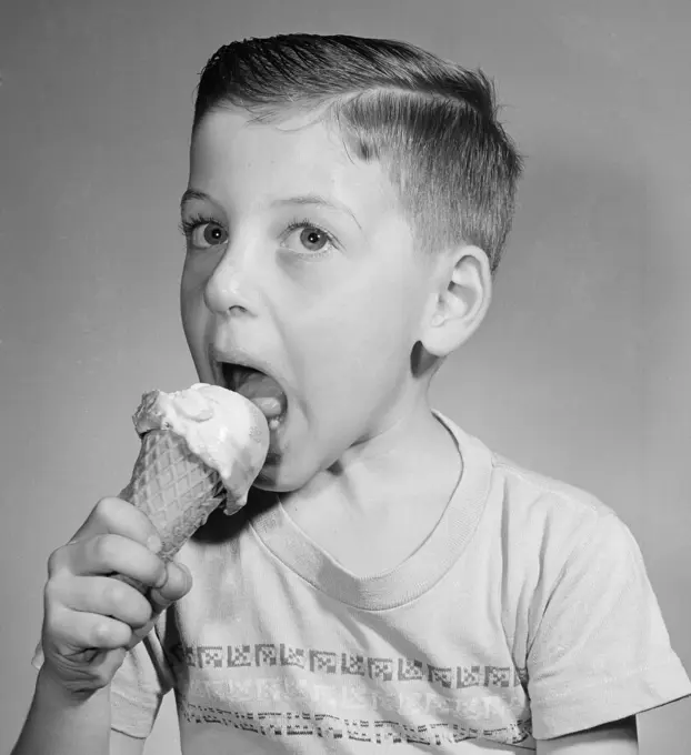 Portrait of boy eating icecream,  studio shot