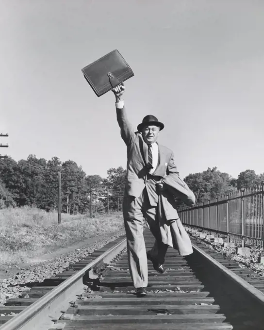 Portrait of a businessman running on railroad tracks