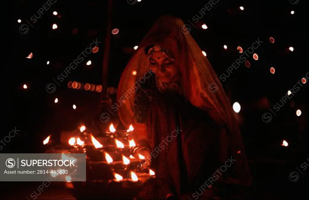 Young woman lighting oil lamps, Punjab, India