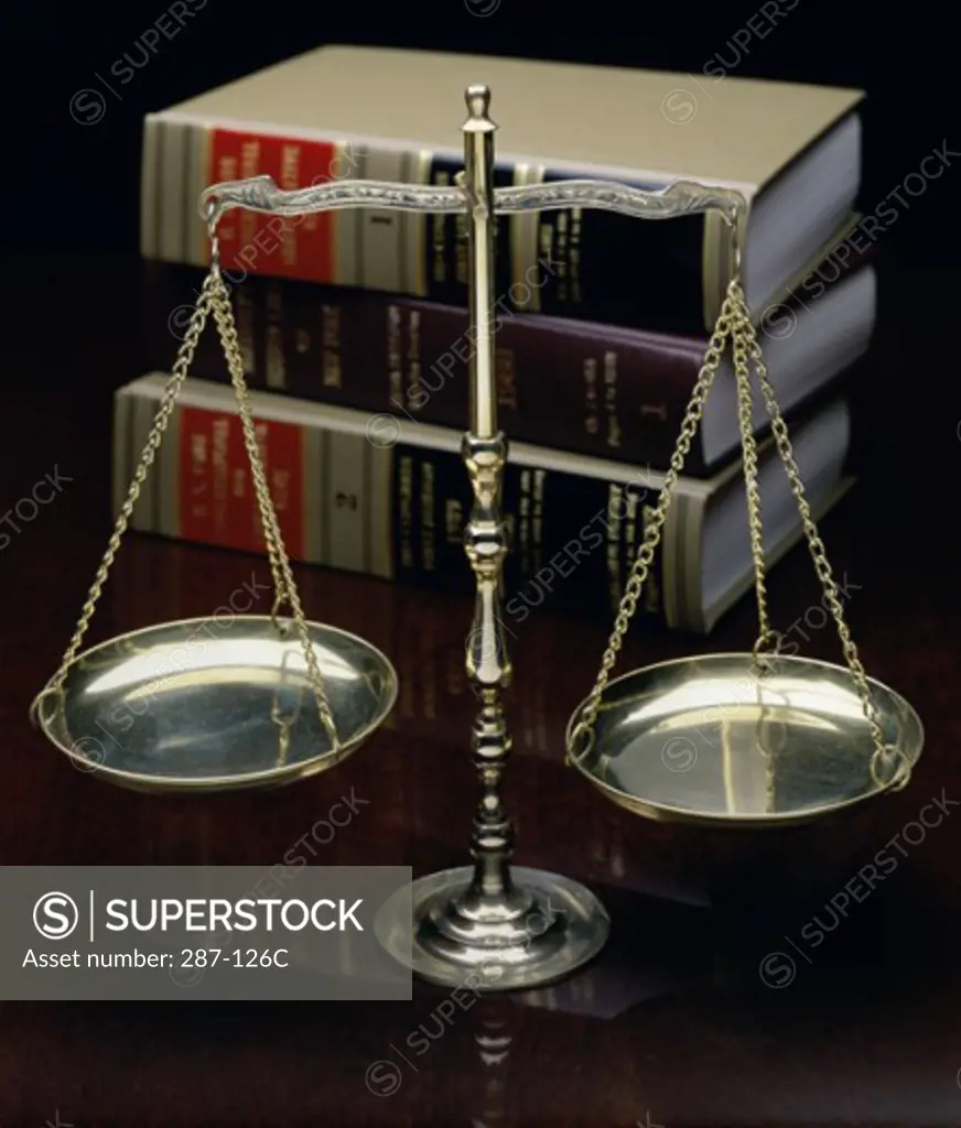 Close-up of a weighing scale in front of a stack of law books