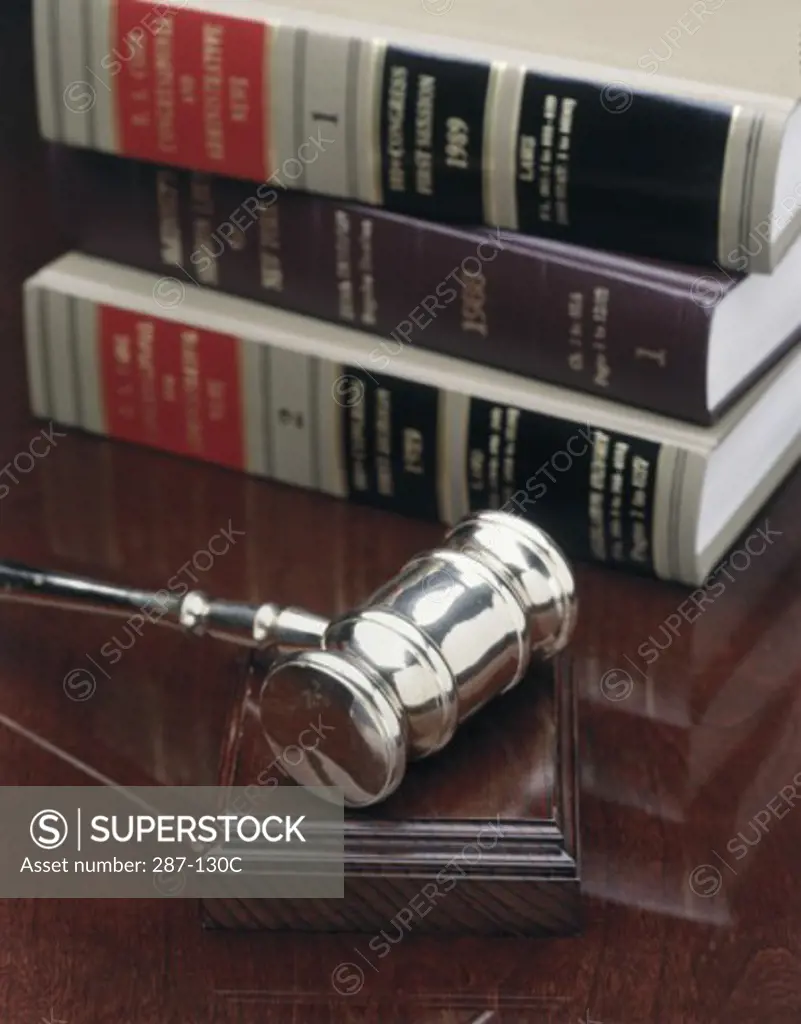 Close-up of a gavel on a wooden block in front of a stack of law books